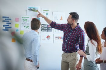 three epople around a white board discussing possible improvement to sustainable packaging solutions